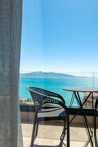a table and chair on a balcony with a view of the ocean at Alpaso Hotel in Sarandë