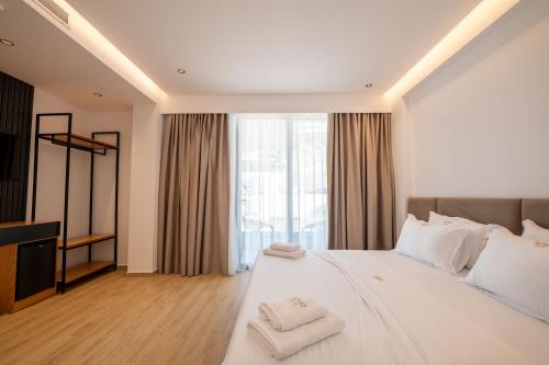 a bedroom with a large bed with two towels on it at Alpaso Hotel in Sarandë