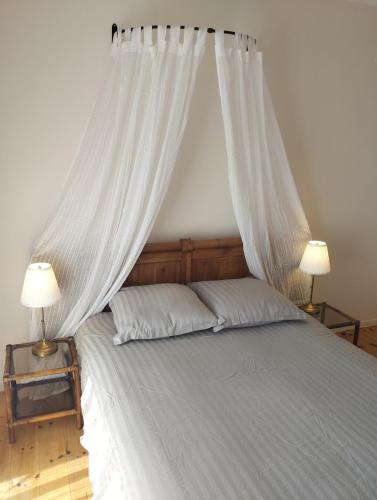 - une chambre avec un lit et des rideaux blancs dans l'établissement Maison avec grand jardin et terrasse plein sud 1, à Lion-sur-Mer