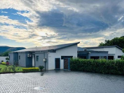 a white house with a driveway in front of it at Pula Nala Lodge Bed & Breakfast in Rustenburg