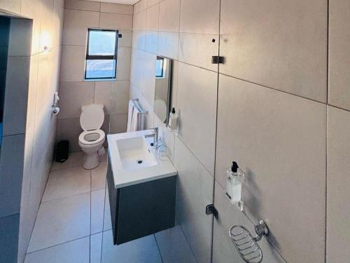 a white bathroom with a toilet and a sink at Pula Nala Lodge in Rustenburg