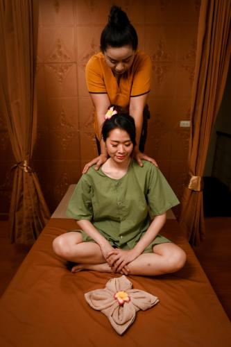 a woman sitting on a bed getting her hair cut at latitude 13 Room & breakfast in Bangkok