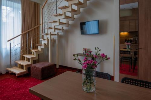 a vase of flowers sitting on a table next to a staircase at Agneta Apartamentai in Druskininkai