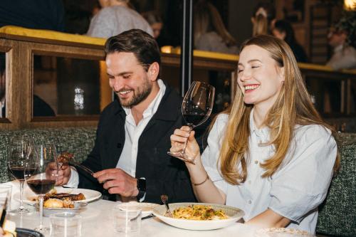 a man and woman sitting at a table with a glass of wine at Hotel Fratelli in Karlstad