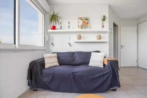 un salon avec un canapé bleu et une fenêtre dans l'établissement Pause à Agde - Avec terrasse, à Agde