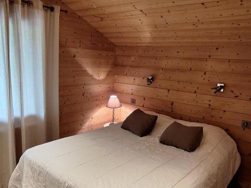 - une chambre avec un lit blanc et un mur en bois dans l'établissement Appartement cosy avec balcon sud, proche pistes ski, animaux admis, parking privé, draps inclus - FR-1-467-113, au Grand-Bornand