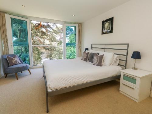 a bedroom with a bed and a chair and windows at 6 Red Sails in Poole