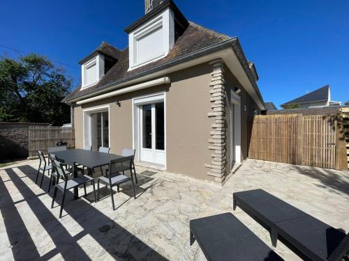 a patio with a table and chairs in front of a house at Horizon Vert by Melrose in Asnelles