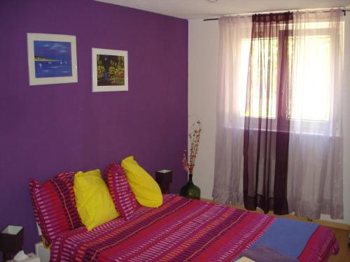 sypialnia z fioletowymi ścianami i łóżkiem z żółtymi poduszkami w obiekcie BnB Le Relais du Château w mieście Aigle