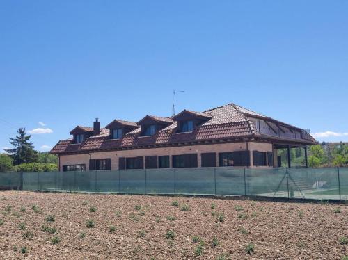 a building with a fence in front of a field at Casa Rural Camino Blanco in Burgos