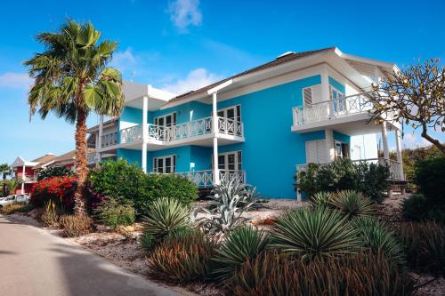 a blue apartment building with a palm tree at Chogogo Dive & Beach Resort Curaçao in Jan Thiel