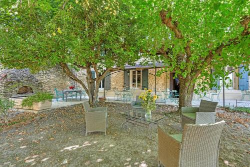 un groupe de chaises et une table sous un arbre dans l'établissement La Bastide des Princes - Aile gauche, à Caderousse