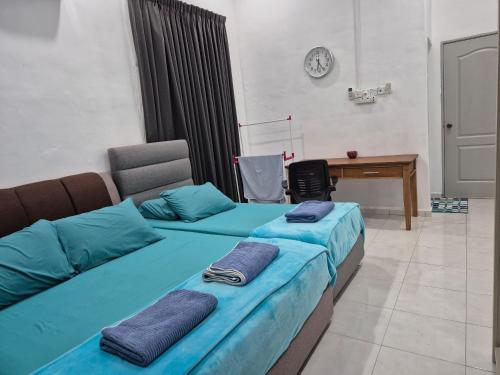 two beds with blue sheets in a room with a desk at Quantum MiCasa in Muar