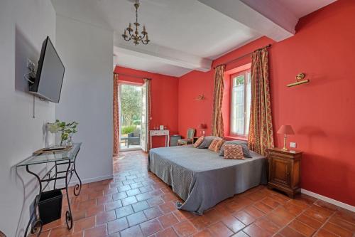 - une chambre avec des murs rouges, un lit et une télévision dans l'établissement La Bastide des Princes - Aile gauche, à Caderousse