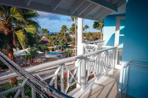 a balcony with a view of the beach and palm trees at Chogogo Dive & Beach Resort Curaçao in Jan Thiel