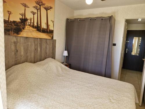 une chambre avec un lit et un tableau au mur dans l'établissement Location T2 climatisé, proche plage, parking privatif à Bormes-les-Mimosas - FR-1-251-747, à Bormes-les-Mimosas