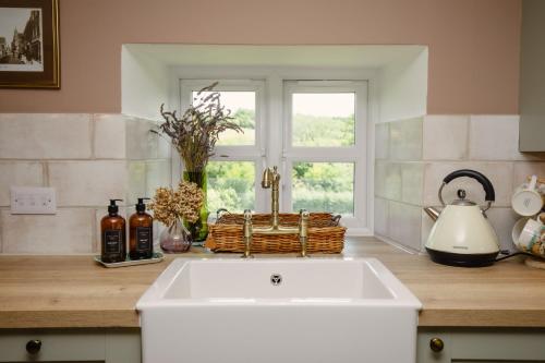 eine Küche mit einer weißen Spüle und einem Fenster in der Unterkunft Thatchers Cottage - Rudge Farm Cottages in Bridport