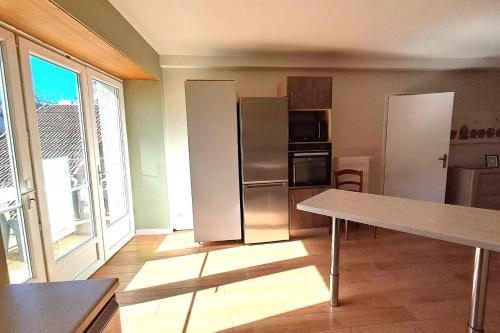 une cuisine avec un réfrigérateur en acier inoxydable et une table dans l'établissement Maison 4 chambres au cœur d’Évaux-les-Bains, à Évaux-les-Bains