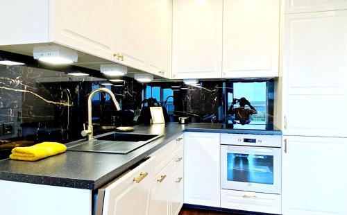 a kitchen with white cabinets and black counter tops at Papiniidu Apartments in Pärnu