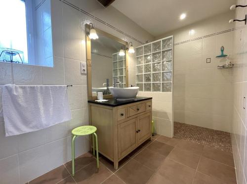 een badkamer met een wastafel, een spiegel en een kruk bij Brecat in Saint-Faust