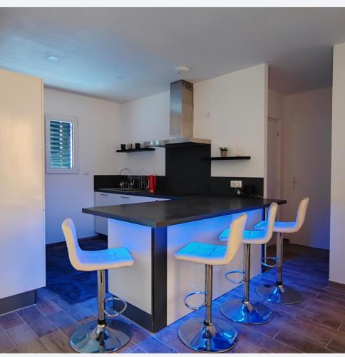 une cuisine avec un comptoir noir et trois tabourets de bar dans l'établissement Maison 6 personne, à Argelès-sur-Mer