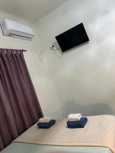 a room with a bed and a tv and towels at Hotel Puerto Libertad - Iguazú in Puerto Libertad