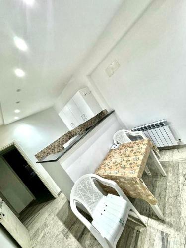a kitchen with two white chairs and a table at Residence dhekra s1 in El Aouina Station