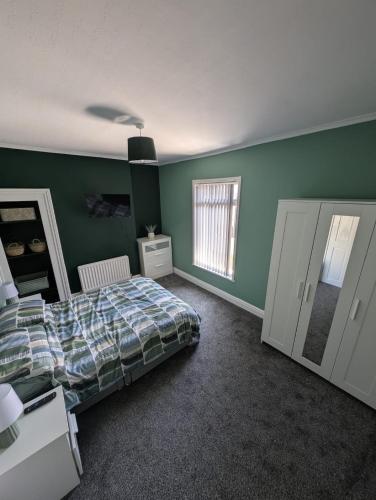a bedroom with green walls and a bed and a mirror at Beautiful 2 Bedroom House Up to 4 people Hull Siemens Holderness road in Hull
