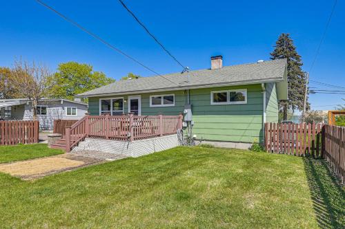 a green house with a wooden fence in a yard at Walk to Flathead Lake Airy Home with Mtn Views! in Polson