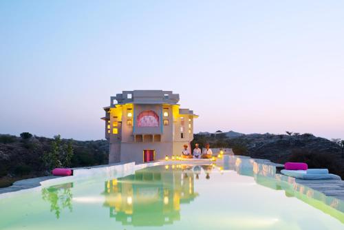 uma piscina de resort com um edifício ao fundo em Brij Lakshman Sagar, Pali em Raipur