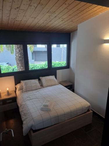 a bedroom with a large bed with two windows at VILLA DEL BOSQUE in Castelldefels