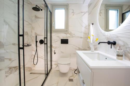a white bathroom with a shower and a sink at Emilia Villas in Agios Nikitas