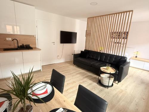 un soggiorno con un divano nero e un tavolo di Apartments KrAnJ - City Studio Katka a Kranj