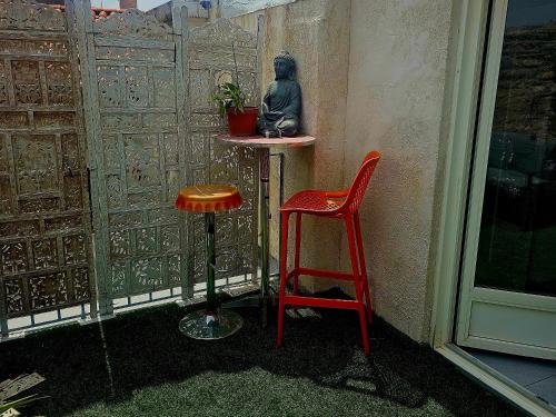 a small table and two red stools on a balcony at F2 appart Millas in Millas