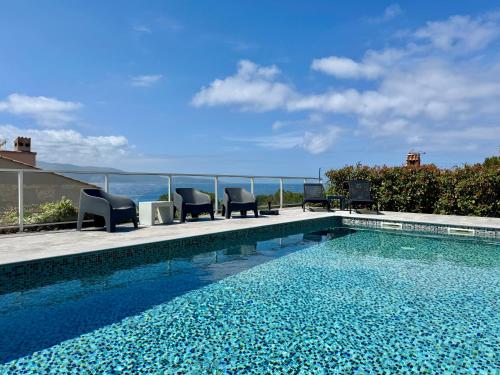 une piscine avec des chaises et l'océan en arrière-plan dans l'établissement Villa le Palmier 10 personnes piscine, vue mer, plage, à Olmeto