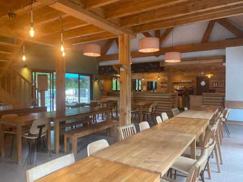 a dining room with wooden tables and chairs at Huttopia Rambouillet in Rambouillet