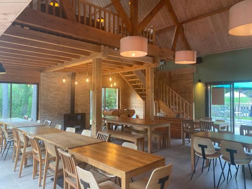 a dining room with wooden tables and chairs at Huttopia Rambouillet in Rambouillet