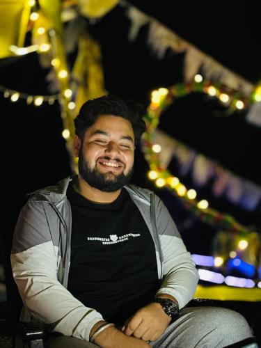 a man smiling while sitting in a chair with his arms crossed at TEC Resort and bar in Dharān Bāzār