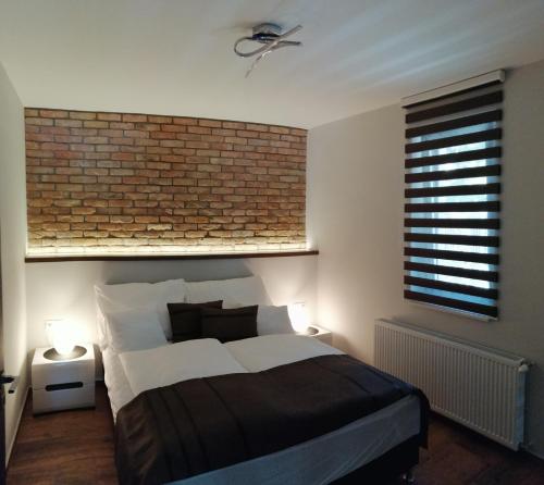 a bedroom with a bed and a brick wall at Griff Apartman in Balatonföldvár