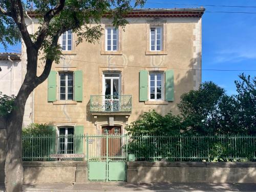 an apartment building with green shutters and a fence at Les volets verts in Saint-Laurent-de-la-Cabrerisse