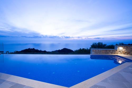 a pool with a view of the ocean at night at Emilia Villas in Agios Nikitas