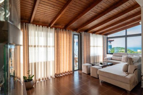 a living room with a couch and some windows at Villa JIOTA in Ksamil