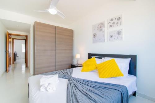 a bedroom with a large bed with yellow pillows at HolidaysPT - Casa da Ria - 2 Bedroom Apartment in Fuzeta