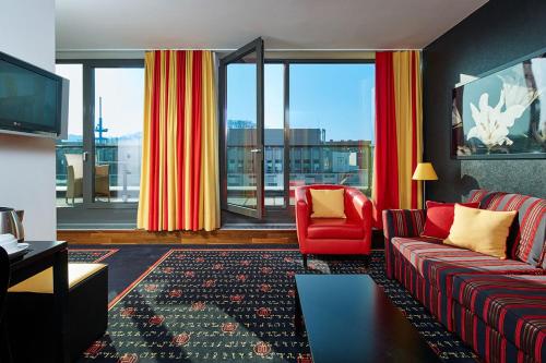 a living room with a red couch and a red chair at OREA Hotel Angelo Praha in Prague