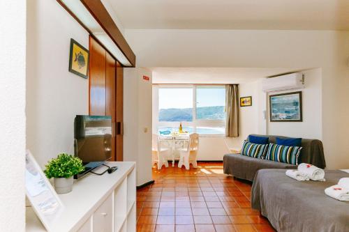 a living room with a couch and a tv at Rent4rest - Sesimbra Ocean View Studio in Sesimbra