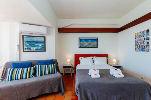 a bedroom with two beds and a couch at Rent4rest - Sesimbra Ocean View Studio in Sesimbra