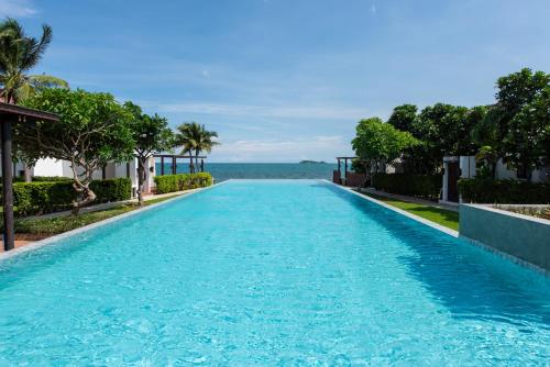 a swimming pool with the ocean in the background at Ban Talay Beach House Rayong Thailand in Ban Pak Nam Krasae