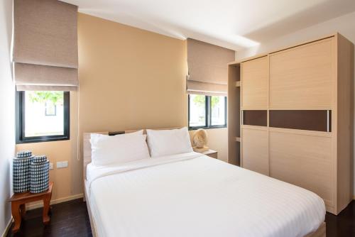 a bedroom with a large white bed and two windows at Ban Talay Beach House Rayong Thailand in Ban Pak Nam Krasae