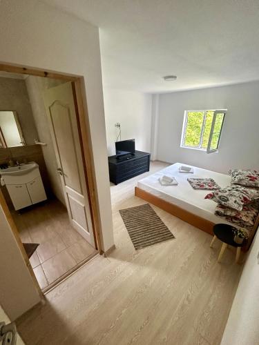 a white room with a bed and a bathroom at La Burlacu in Eşelniţa