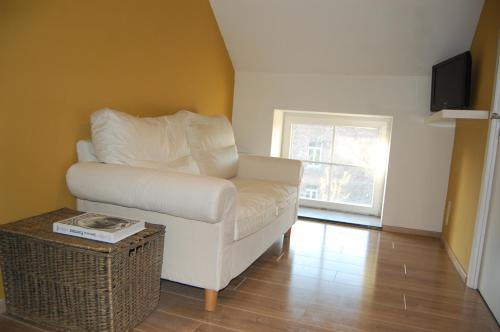 a living room with a white chair and a table at Gîte de la Fontaine in Beauraing